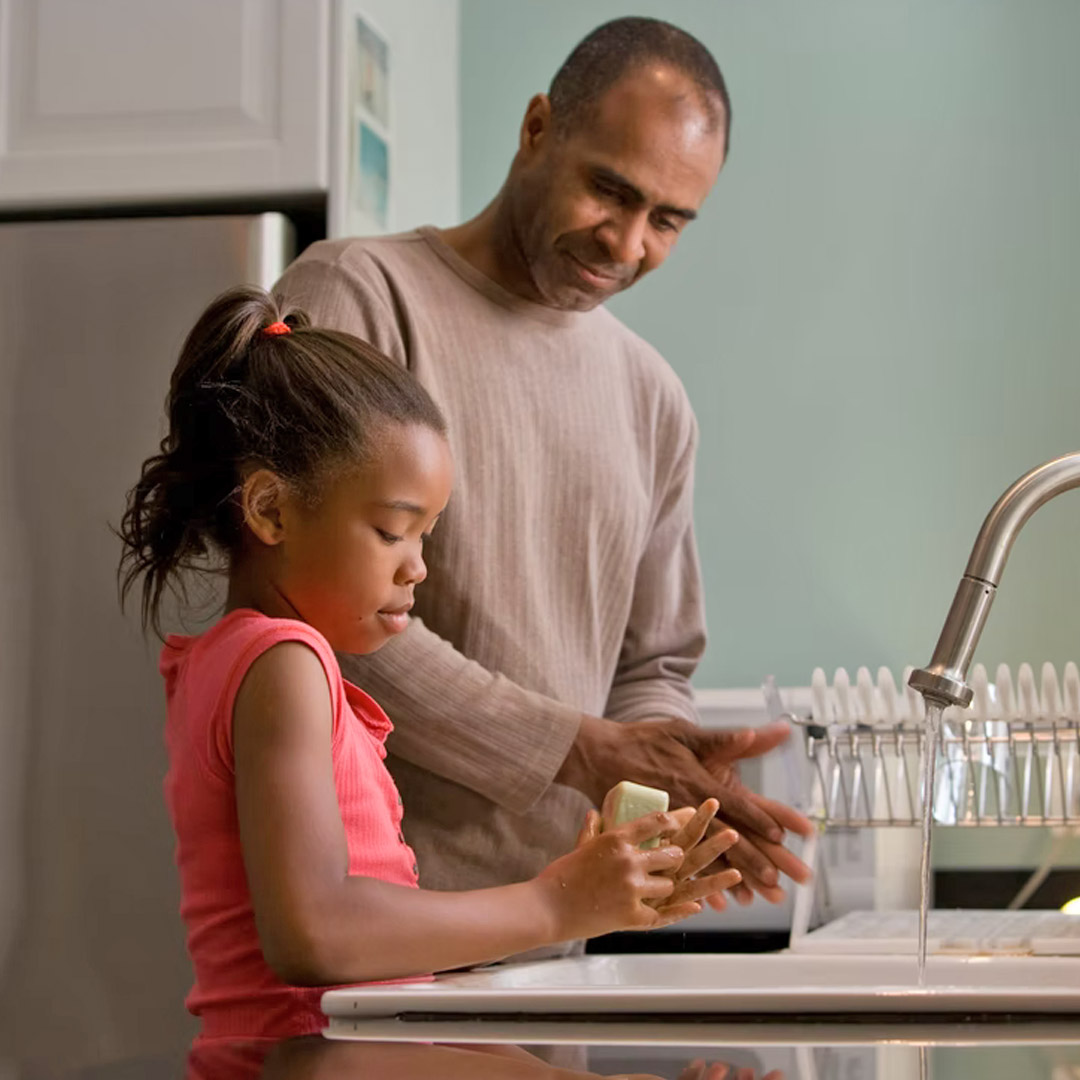 A father washing dishes with his daughter