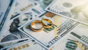wedding rings stacked on one-hundred dollar bills