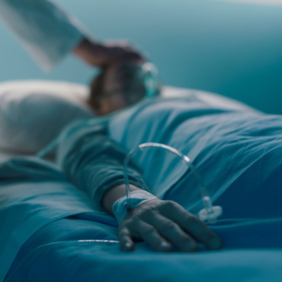 a person in a hospital bed wearing an oxygen mask