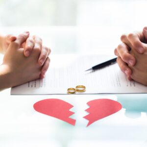 two people with hands folded on divorce paperwork