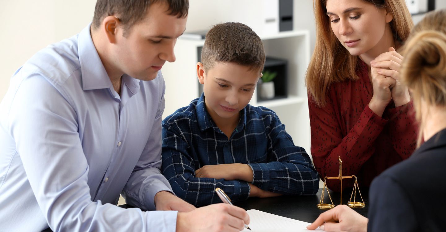 parents signing paperwork with their child and a third party present
