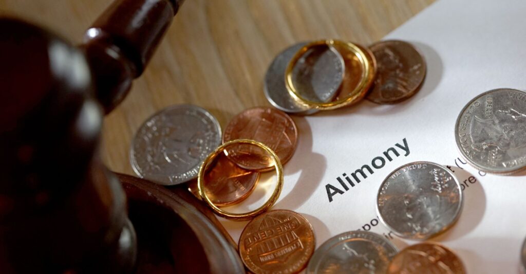 Alimony concept with paperwork, money, and a pair of wedding rings
