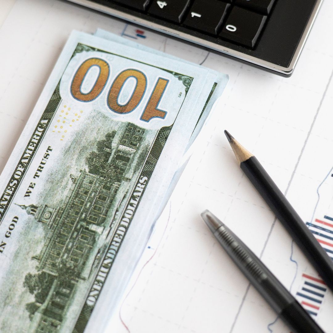 one hundred dollar bill next to pencils 